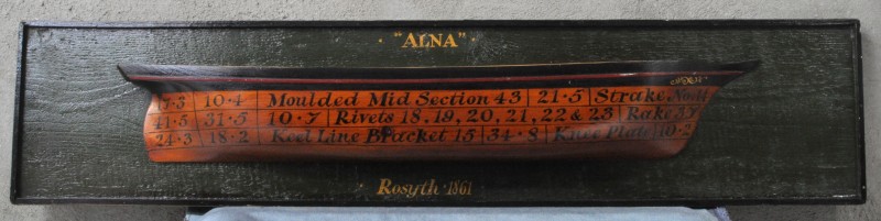 “Alna”. Een plaquette van gepolychromeerd hout met een dwarsdoorsnede van een schip.