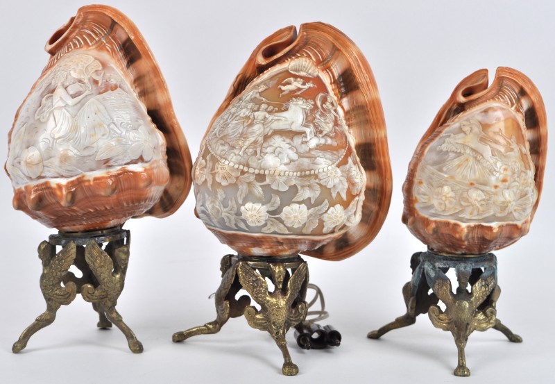 Drie schemerlampjes gevormd door een in camee gesculpteerde schelp, met een mythologische voorstelling. Op een vergulde driepoot. Medio XXste eeuw.