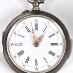 Een koperen horlogehouder in de vorm van een hondje, vier horloges, een oud kompas, een reiswekker en een thermometer met een tinnen montuur.