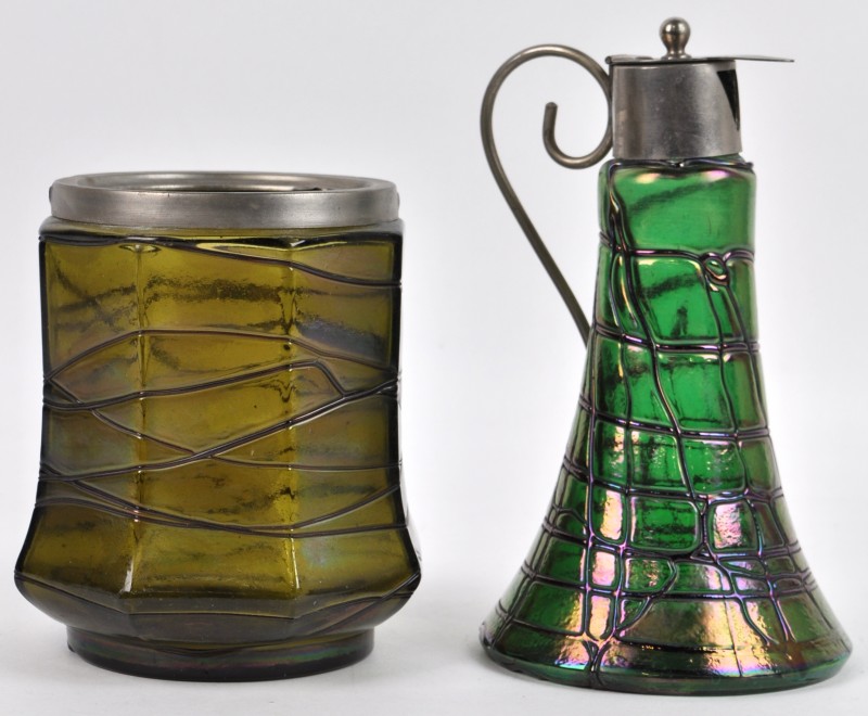 Een klepkannetje en een octagonaal vaasje van iriserend glas in art nouveaustijl. Beide met metalen montuur, maar één beschadigd. Vermoedelijk Pallme König & Habel.
