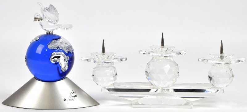 Een kandelaar van geslepen kristal, opgebouwd uit drie globes en een vredesduif op een wereldbol. Beide gemerkt en het tweede gedateerd 2000.