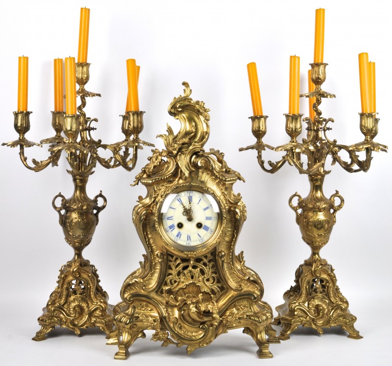 Koperen klokstel in Lodewijk XV-stijl. Twee kandelaars en een pendule.