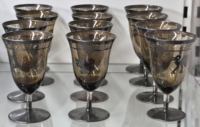 Twaalf glazen van gerookt glas met een verzilverd decor van dieren in precolumbiaanse stijl en een meander onder de rand.