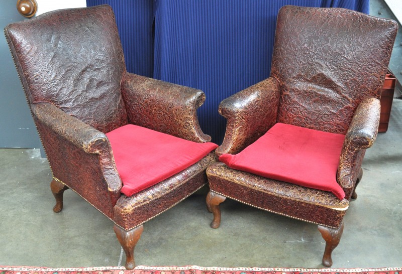 Twee fauteuils met een lederen relëfbekleding met florale motieven.