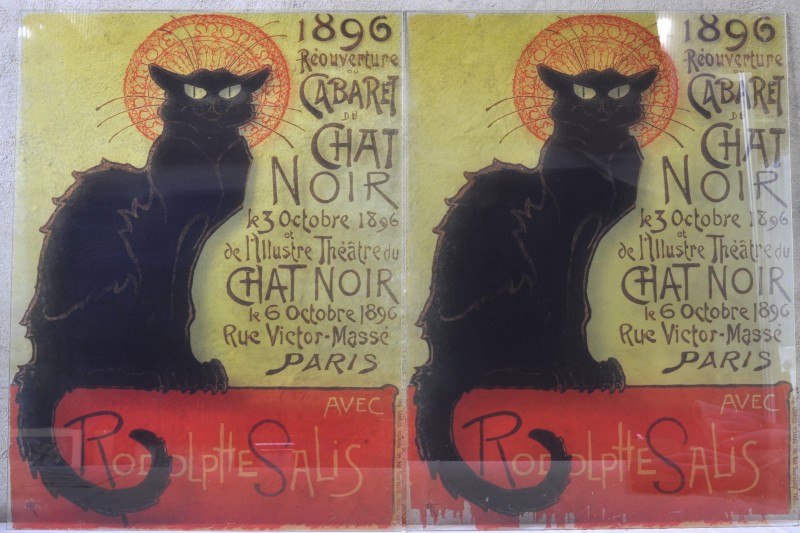 Een paar glasramen met afbeeldingen van oude affiches van het cabarettheater “Le Chat noir” te Parijs.