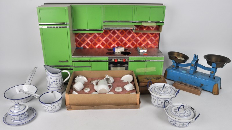 Lot speelgoed: een blikken keuken, een houten spaarpot, een kleine balans met gewichten, een aantal geëmailleerde metalen kannetjes met een immortelle de Saxe-decor, een porseleinen theeserviesje in zijn doos.