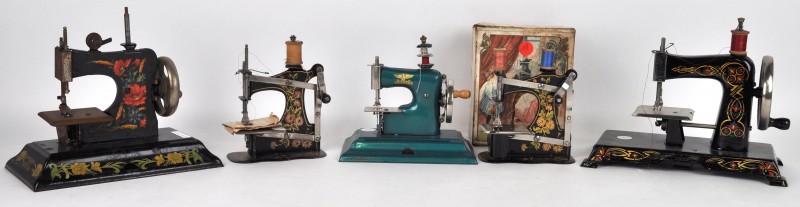 Vijf diverse oude naaimachines van gelakt metaal, waarvan één met de oorspronkelijke doos.