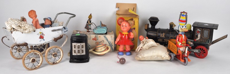 Lot speelgoed: een blikken locomotief, een kinderwagentje met diverse kleine poppen, een blikken vogel op een karretje, een wandelend popje in zijn doosje, een blikken meisje met kinderwagen, een rammelaar in zijn doos.