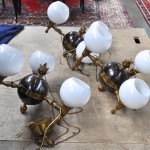 Negen identieke bolvormige koperen luchtertjes met drie lichtpunten met bollen glazen kapjes en centraal bekroond met een vlammetje.