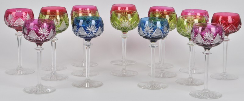 Een serie van zestien glazen van geslepen kristal in diverse kleuren.