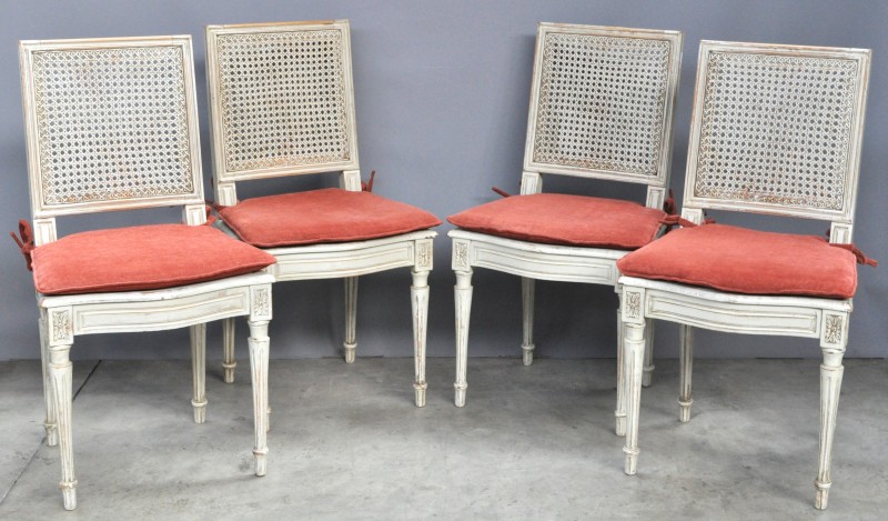 Vier stoelen van gesculpteerd en witgepatineerd notenhout in Lodewijk XVI-stijl met gecanneleerde poten en een gecanneerde rug en zit.