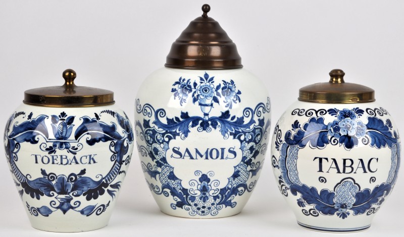 Drie tabakspotten van blauw en wit Delfts aardewerk met messingen deksels in diverse uitvoeringen.