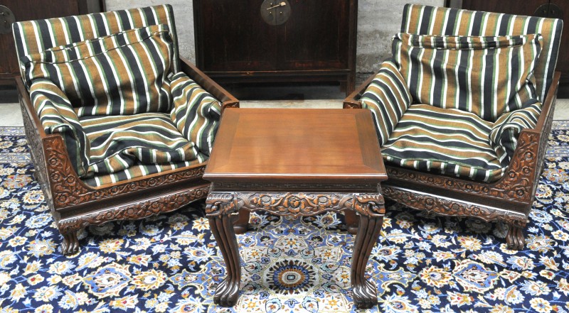 Een paar fauteuils en een bijpassend salontafeltje van gesculpteerd hout in Chinese stijl.