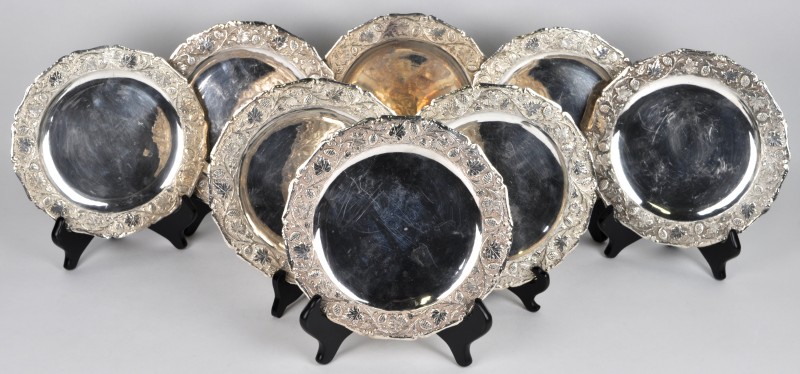 Een lot van acht zilveren schotels, versierd met druivenranken in reliëf op de vleugel.