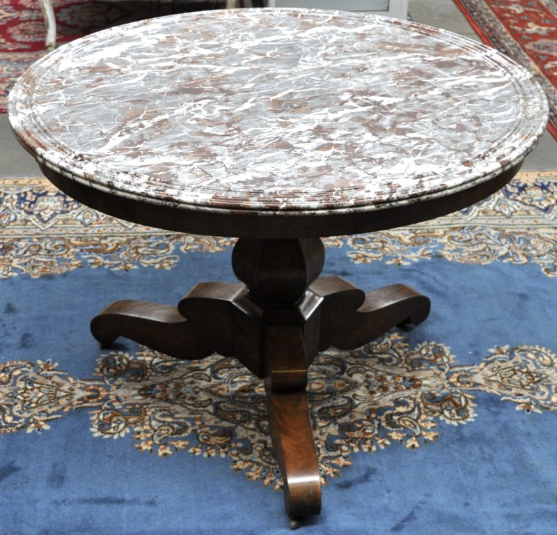 Een ronde tafel van mahoniehout op een centrale driepoot met een marmeren blad. XIXe eeuw.