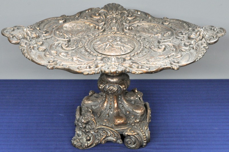 Een milieu de table op hoge voet van verzilverd metaal in barokke stijl.