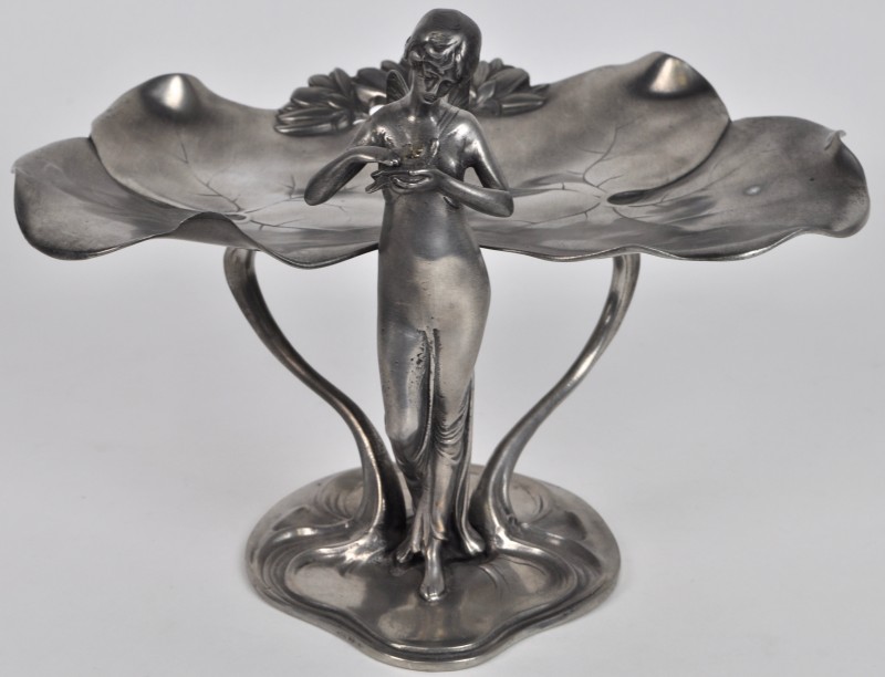 Een vide-poche van tin in de vorm van leliebladeren en gedragen door een nimf met een duif. Tijdperk Art Nouveau.