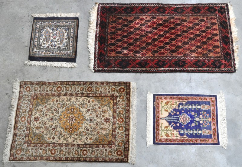 Een lot van vier kleine handgeknoopte tapijtjes, waarvan twee van zijde.
