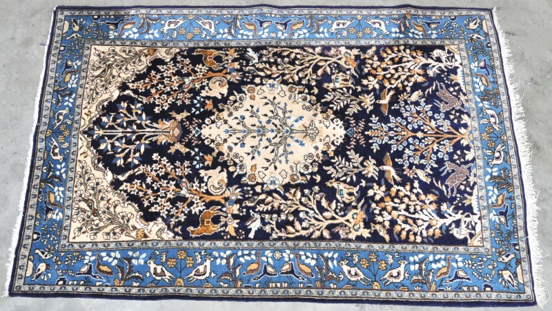 Een handgeknoopt Perzisch tapijt van wol en katoen met afbeeldingen van dieren in zijde.