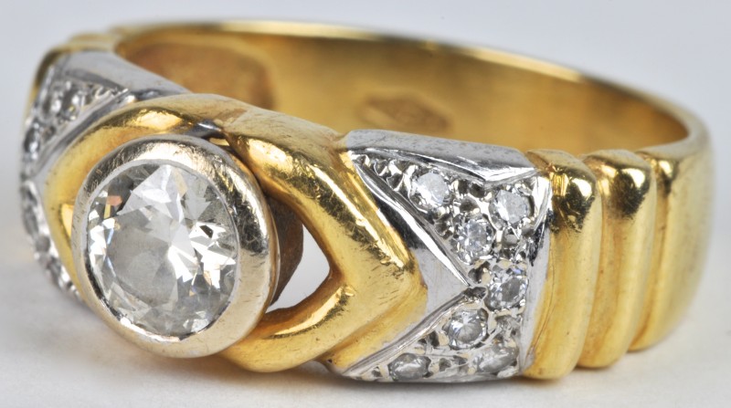 Een 18 karaats wit en geel gouden ring bezet met een centrale diamant van ± 0,40 ct. en met diamanten met een gezamenlijk gewicht van ± 0,20 ct.