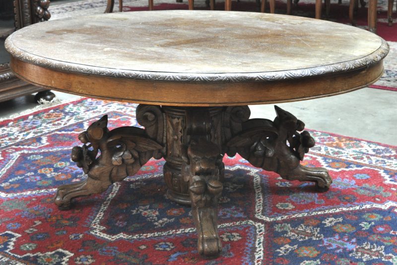 Een salontafel van gesculpteerd eiken hout in renaissancestijl op centrale voet, eindigend in vier gevleugelde leeuwen.