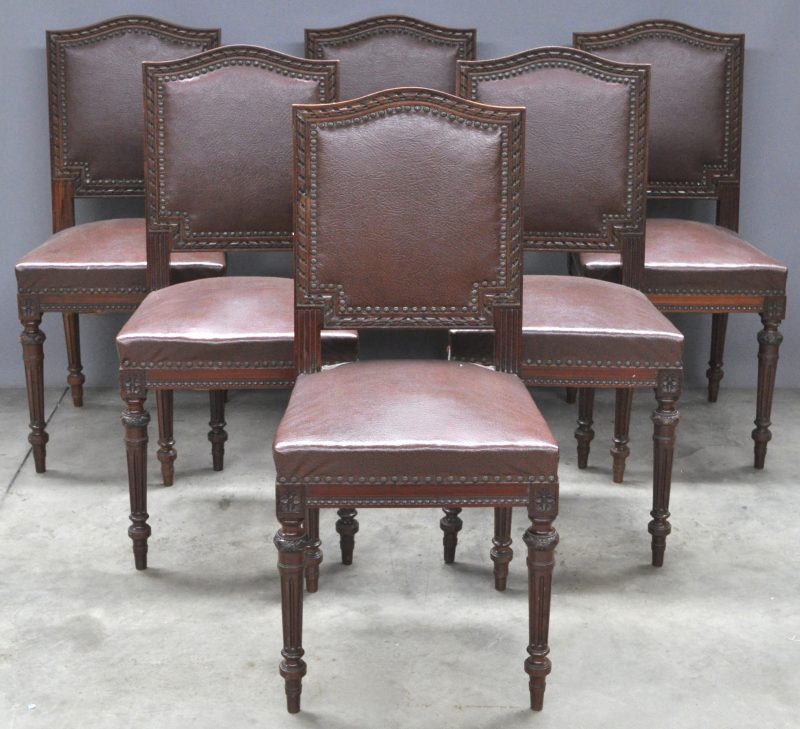 Zes stoelen van gesculpteerd hout in Lodewijk XVI-stijl met imitatielederen bekleding.