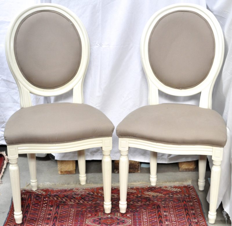 Twee stoelen van witgepatineerd hout met beige stoffen bekleding.