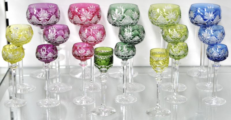 Een serie van geslepen kristallen glazen in diverse kleuren, bestaande uit zes en twee borreltjes, zes aperitiefglaasjes en vijf wijnglazen.