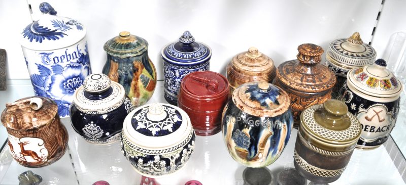 Een verzameling van dertien tabakspotten van aardewerk en steengoed in verschillende uitvoeringen.