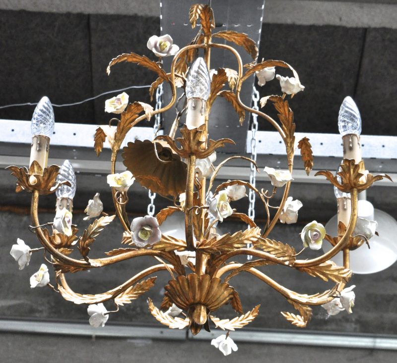Een koperen luchter met zes lichtpunten in de vorm van gebladerte en versierd met porseleinen bloemen.