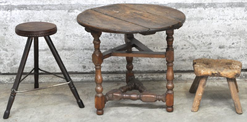 Een rond eikenhouten tafeltje met vier poten met tussenverbinding, een rustiek melkstoeltje en een taboeretje, gedeeltelijk opgebouwd uit oudere elementen.