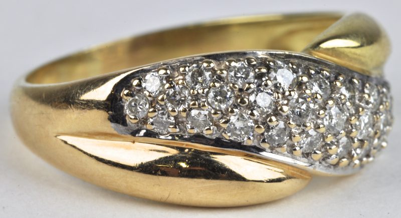 Een 18 karaats wit en geel gouden ring bezet met briljanten met een gezamenlijk gewicht van ± 1 ct.