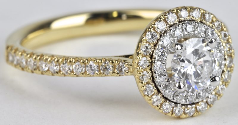 Een 18 karaats wit en geel gouden ring bezet met diamanten met een gezamenlijk gewicht van ± 0,58 ct. en een centrale solitair van ± 0,37 ct.