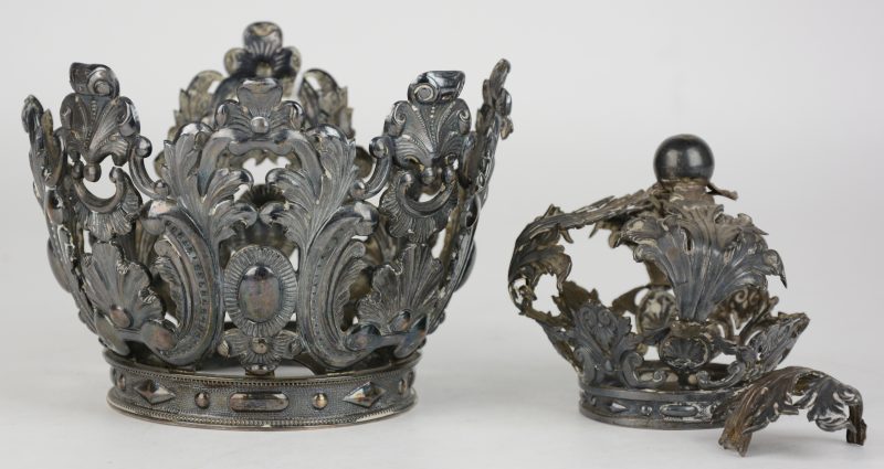 Twee kronen van heiligenbeelden van gedreven zilver in barokke stijl waarvan één kleinere en beschadigd.