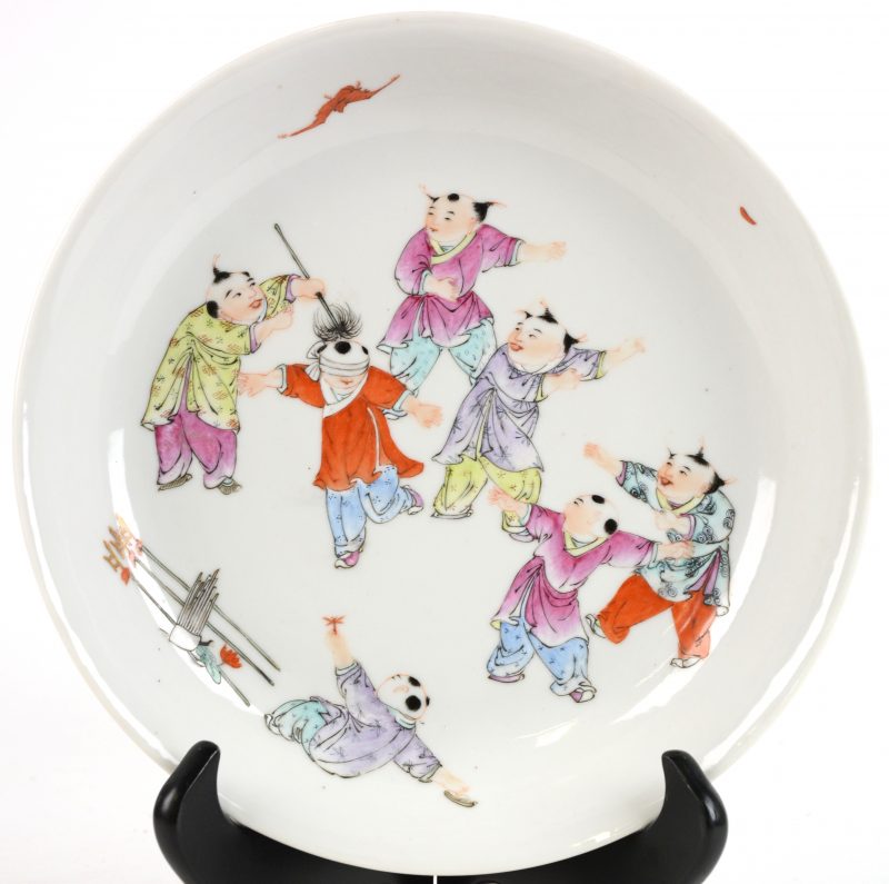 Een bord van Chinees porselein met een meerkleurig decor van spelende kinderen. Onderaan gemerkt. XXe eeuw. (één letsel aan de rand).