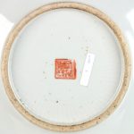 Een schotel van Chinees porselein met een famille rosedecor. Onderaan gemerkt. Randschilfer.