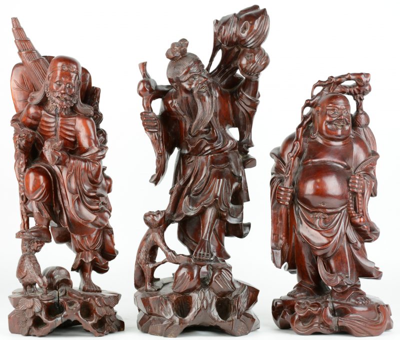 Een Chinese wijze met aapje en perzikken, een wijze met hoen en een voorstelling van Boeddha van gesculpteerd hardhout.