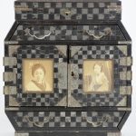 Een Japans juwelenkabinetje van zwartgelakt hout en koper met twee foto’s in de deurtjes. Jaren ‘30.