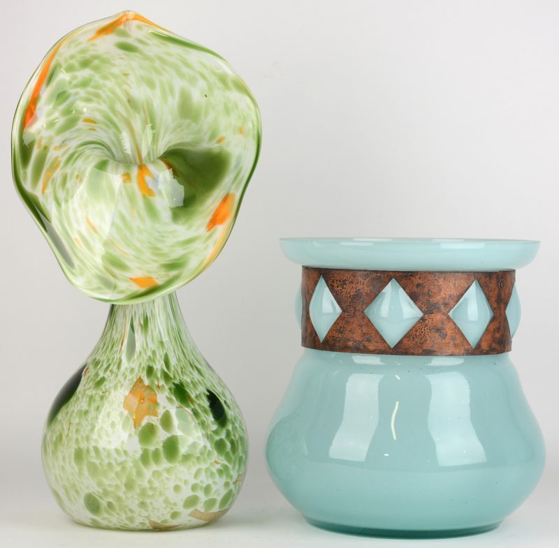 Twee verschillende glazen, waarvan één bloemvormig van glaspasta en een ander van blauw glas met een koperen fries.