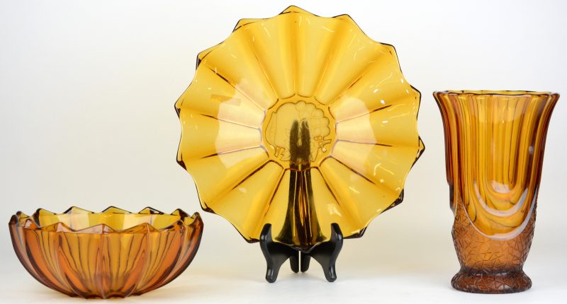 Een lot amberkleurig glaswerk, bestaande uit een fruitschaal met onderschotel en een vaas naar ontwerp van Henri Heemskerk. Belgisch werk, de laatste Scailmont. Tijdperk Art deco.