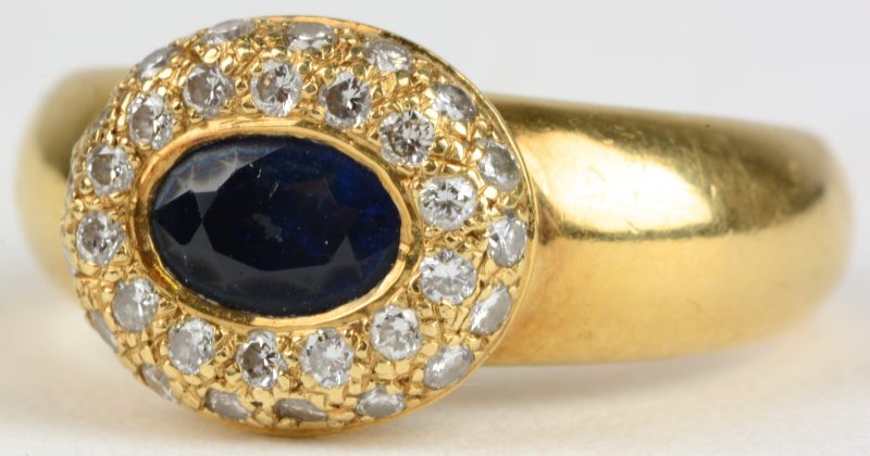 Een 18 karaats geel gouden ring bezet met diamanten met een gezamenlijk gewicht van ± 0,40 ct. en een centrale saffier van ± 0,70 ct.