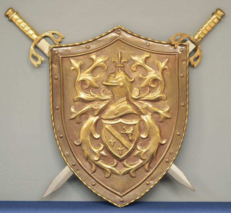 Een replica wapenschild  van rood koper met twee zwaarden.