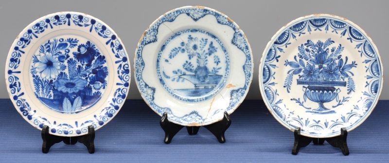 Drie verschillende borden van blauw en wit aardewerk met bloemendecors. Delft, XVIIIe eeuw. Eén zwaar gerestaureerd.