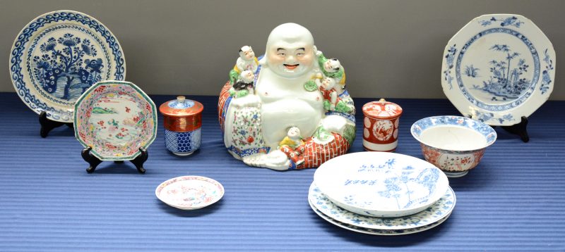 Een lot porselein en aardewerk, bestaande uit twee Japanse dekselpotjes, vier verschillende borden met een blauw en wit decor (waarvan één Delfts), een kommetje en een zittende Boeddha met zotjes. Meerdere restauraties.
