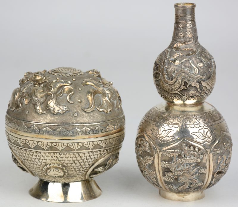Een klein zilveren kalebasvaasje, versierd met mythologische wezens en een rond dekseldoosje van zilver, versierd met goudvissen in het decor. Chinees werk.