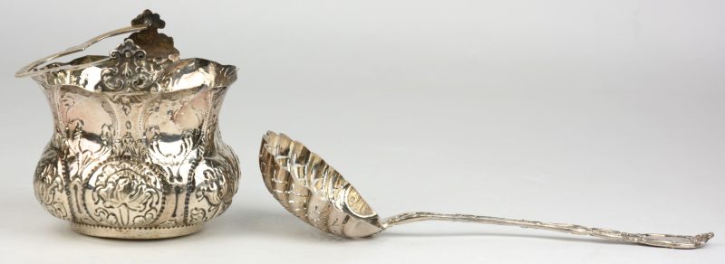 Een keteltje van gedreven zilver en een opengewerkte lepel in Lodewijk XV-stijl.