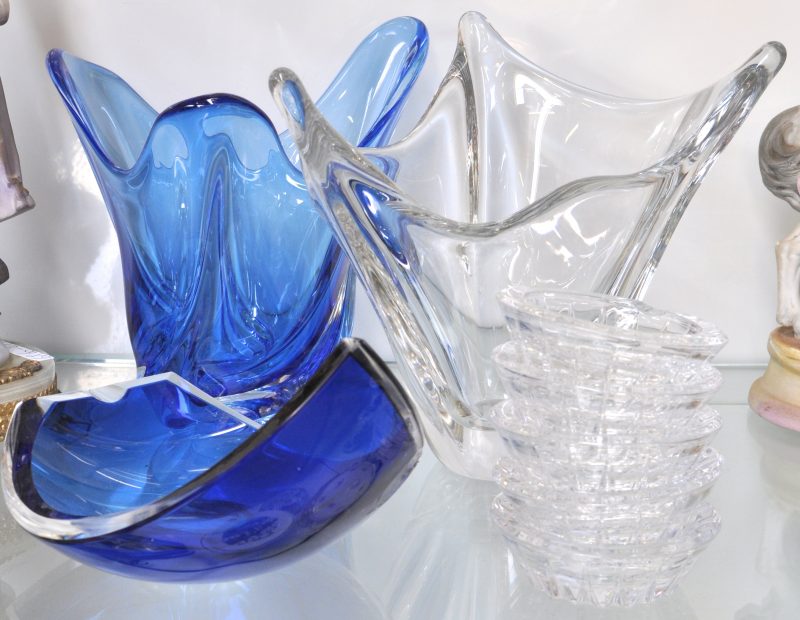 Een lot kristal, bestaande uit een blauwe en een kleurloze designvaas, vijf kleurloze asbakjes en en een blauwe asbak met schilfer. Allen gemerkt.