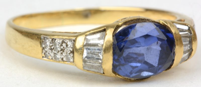 Een 18 karaats geel gouden ring bezet twee diamanten en baguetten met een gezamenlijk gewicht van ± 0,30 ct. en een saffier van ± 0,75 ct.
