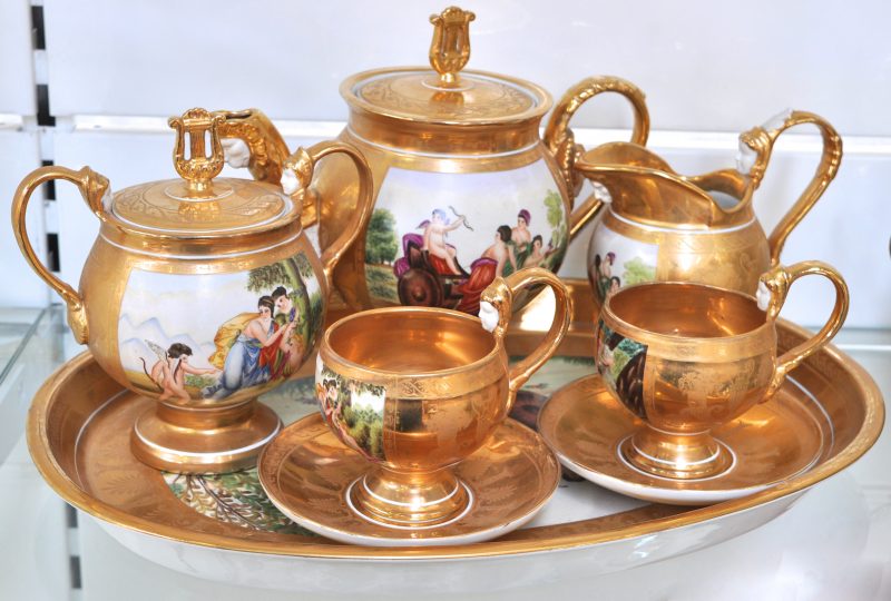 Een achtdelig theeserviesje van meerkleurig en verguld porselein in empirestijl, versierd met classicistische decors. Onderaan gemerkt.