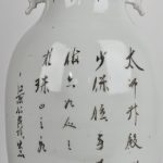Een balustervaas van Chinees porselein met een fô-honden in ijzerrood en kalligrafische tekens in het decor. XIXde eeuw.